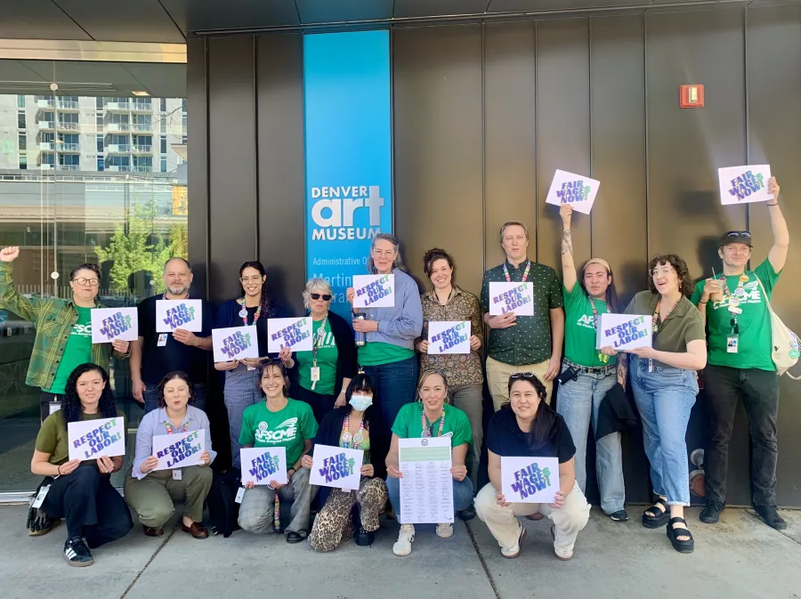 DAMWU workers stand outside of the Denver Art Museum holding signs to celebrate their win